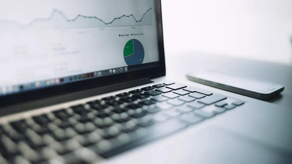Laptop on a desk with line charts on its screen