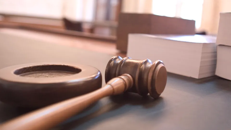 Wooden gavel resting on a desk beside stacks of paper