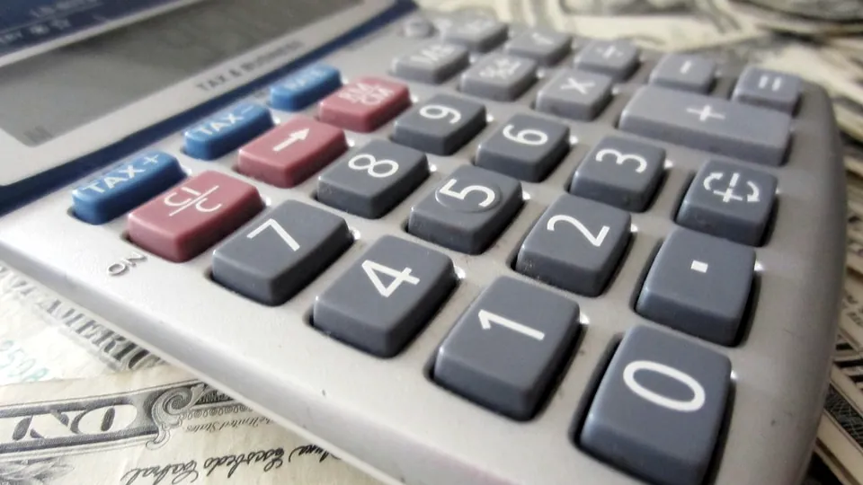 Close-up of a calculator keypad lying on US dollar bills