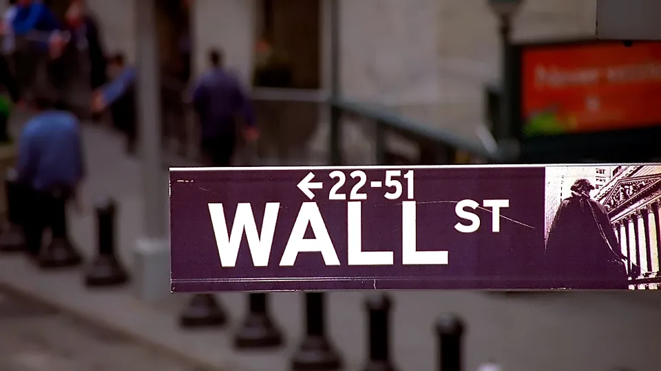 Wall Street street sign with the financial district blurred behind