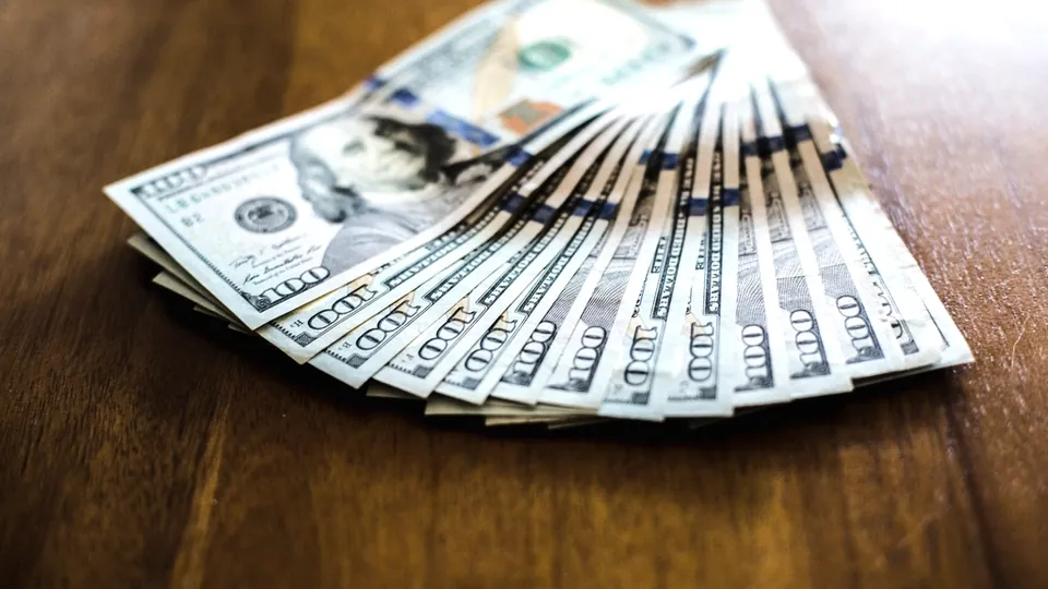 Fan of US dollar banknotes spread on a wooden table