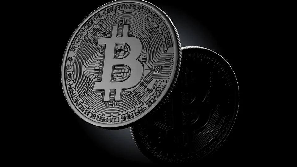 A single silver replica bitcoin coin lit against a black background