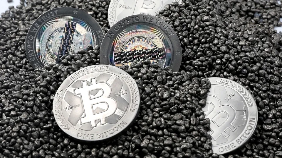 Silver replica bitcoin coins resting on a bed of dark granules